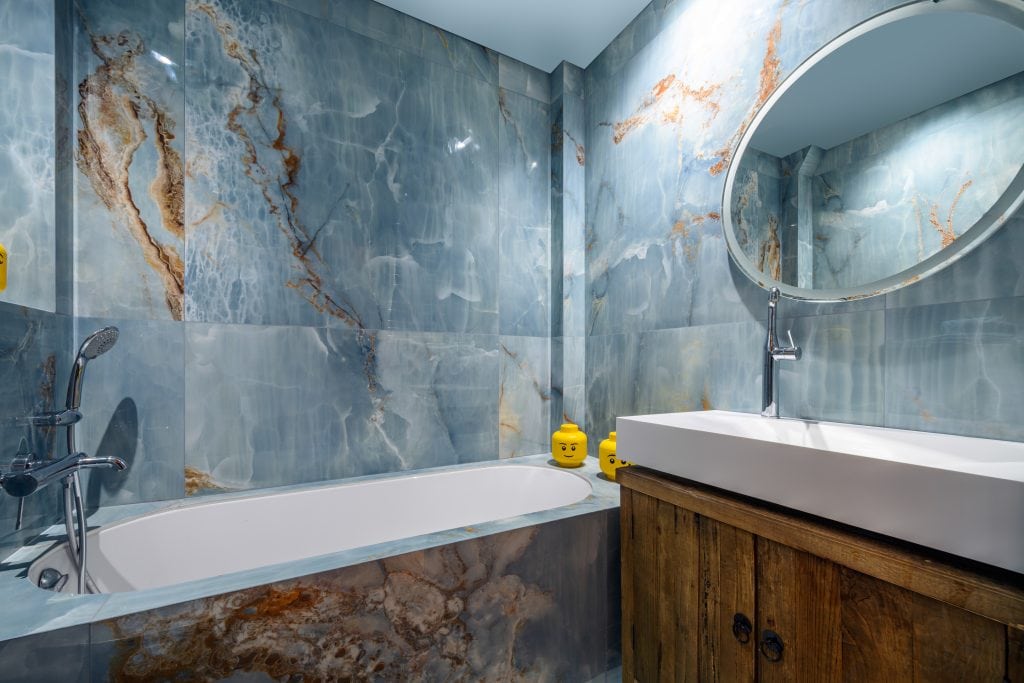 Bathroom with blue marble walls, bathtub, and modern sink vanity.