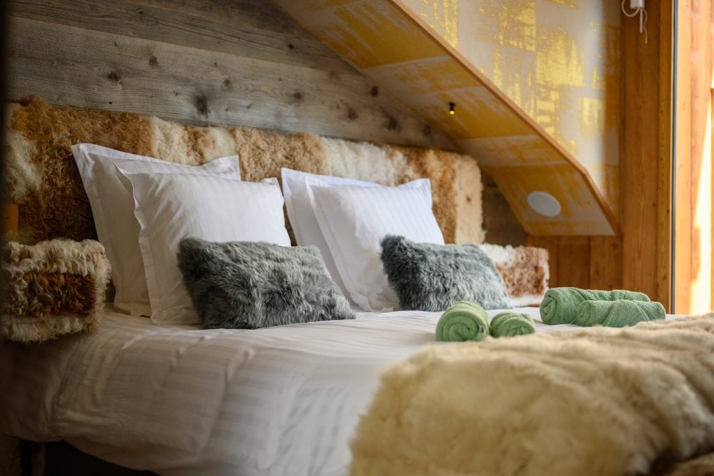 Close-up of a luxury bed with fur textures and soft pillows in the master suite.