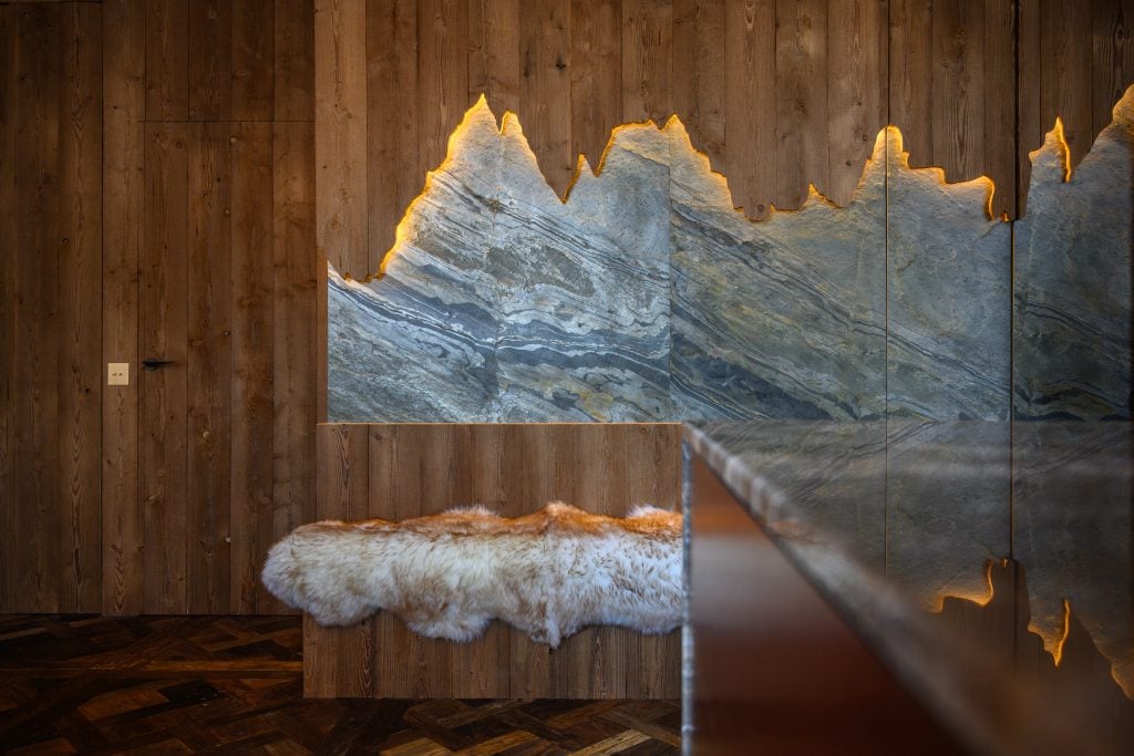 Decorative stone wall with mountain-shaped lighting and fur bench.